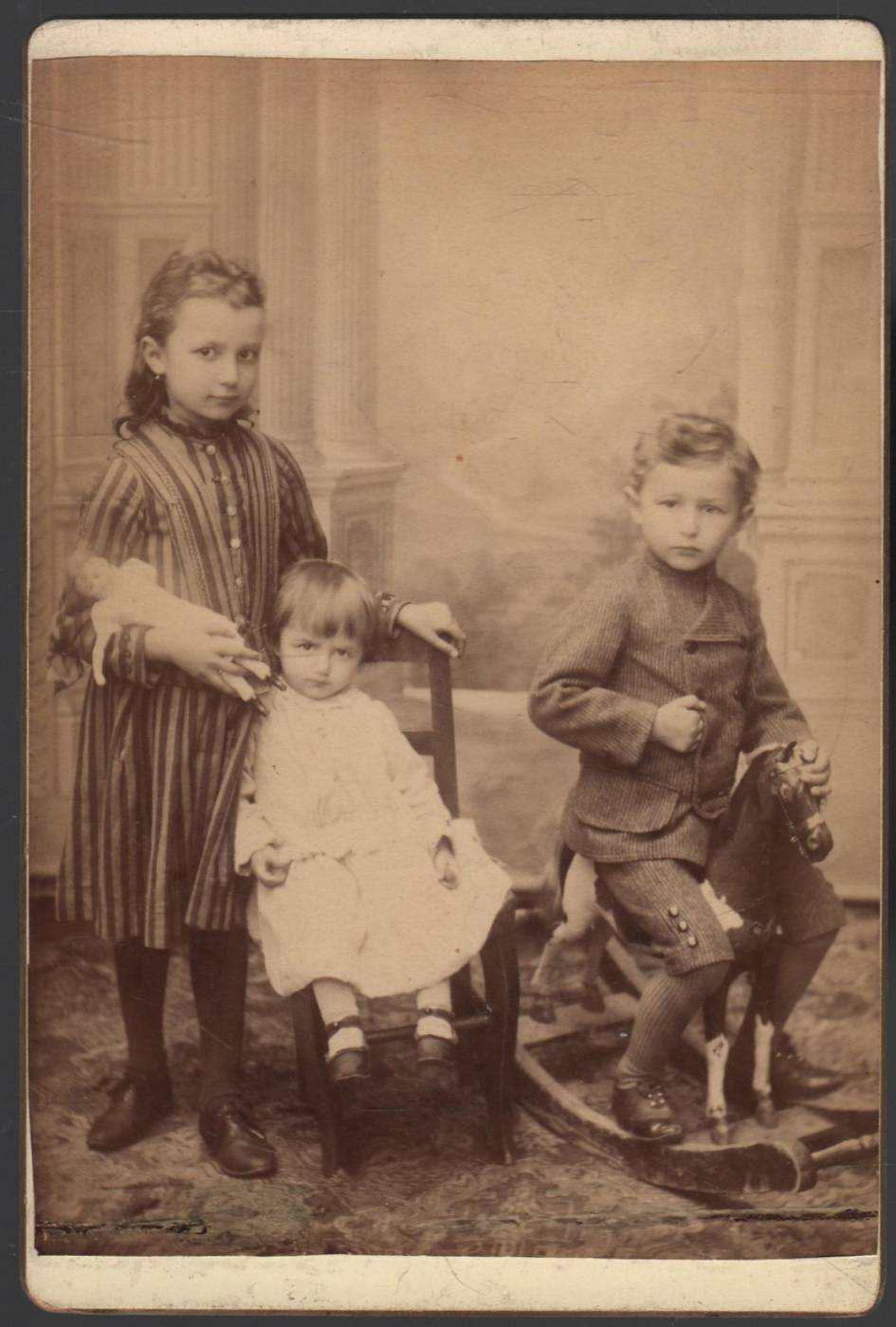 fotografie tří dětí, chlapec na houpacím koníkovi 